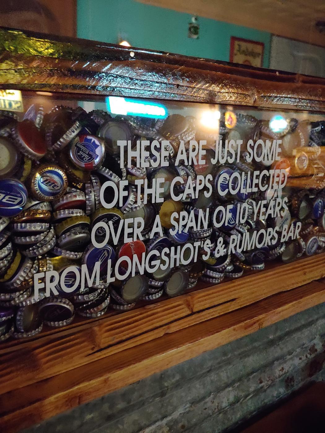 The wall of bottle caps with its hand-lettered sign